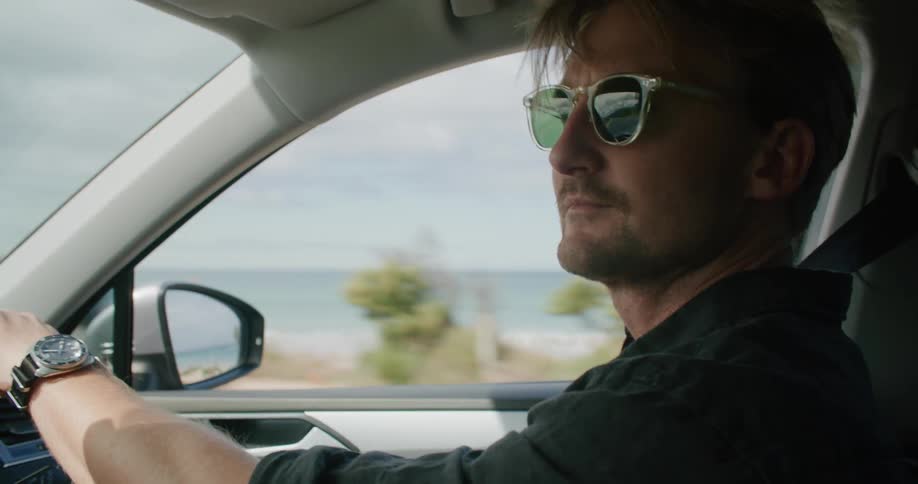 Man drives down road with beach on the side