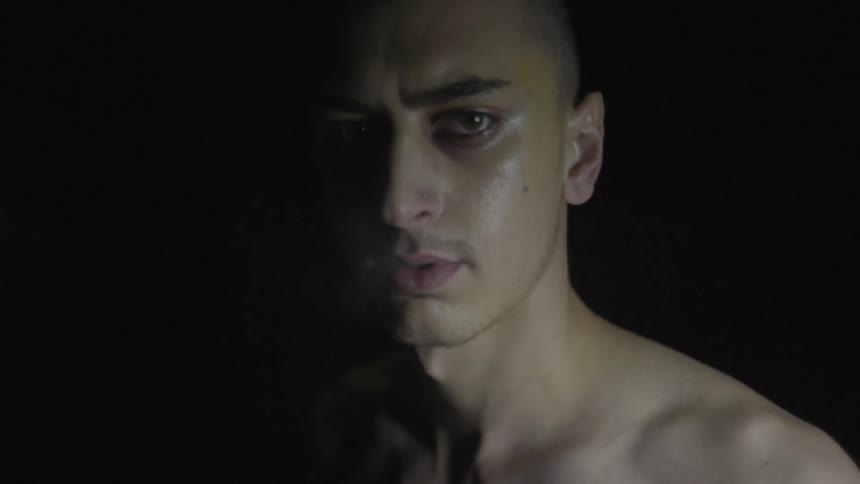 A man looks to his side in a dark area