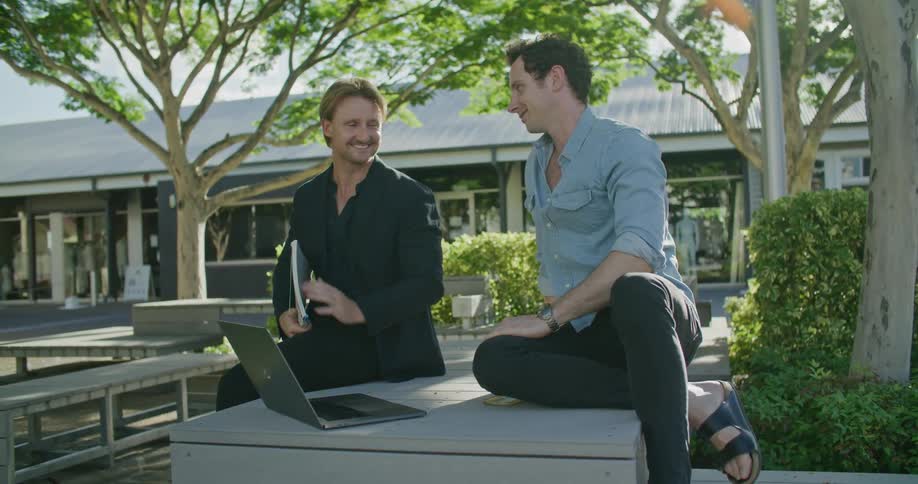 Two men that are sitting around outside talking