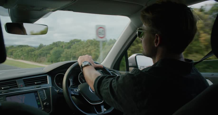 A man drives a vehicle down a road on a cloudy day