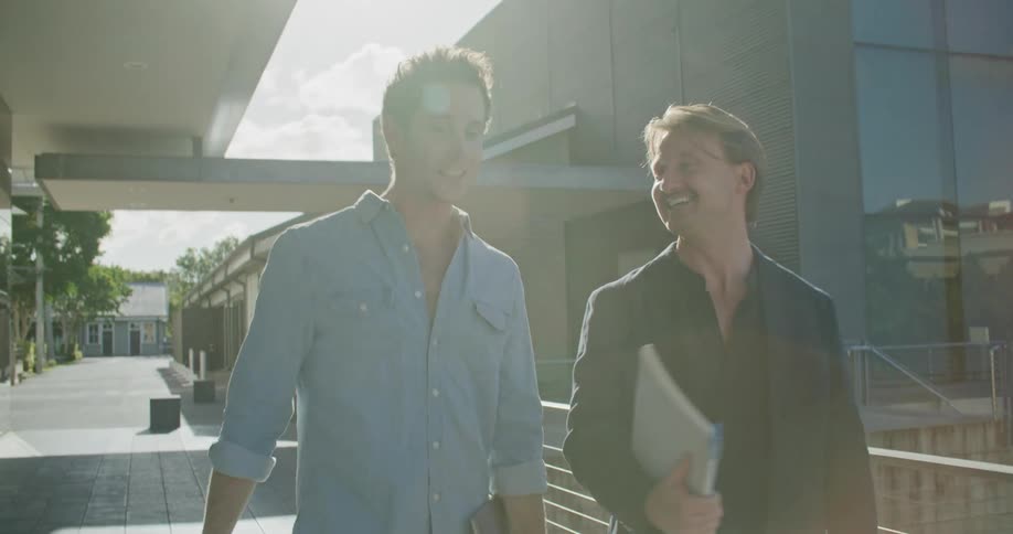 Two men walk and talk outside of the office building