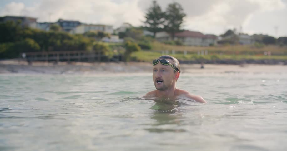 A man wearing goggles swimming in the ocean