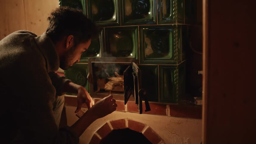 A man is lighting some tinder in the chimney