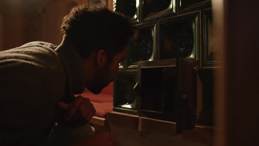 A person with a sweater in a room cleaning out a furnace