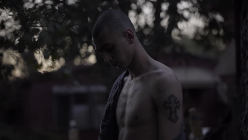 A man is standing shirtless and looking down