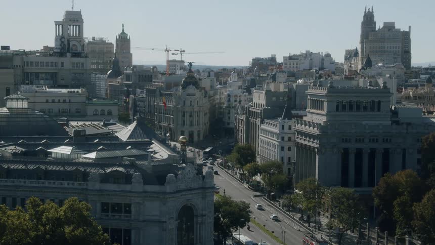 Traffic flows along street past ornate buildings