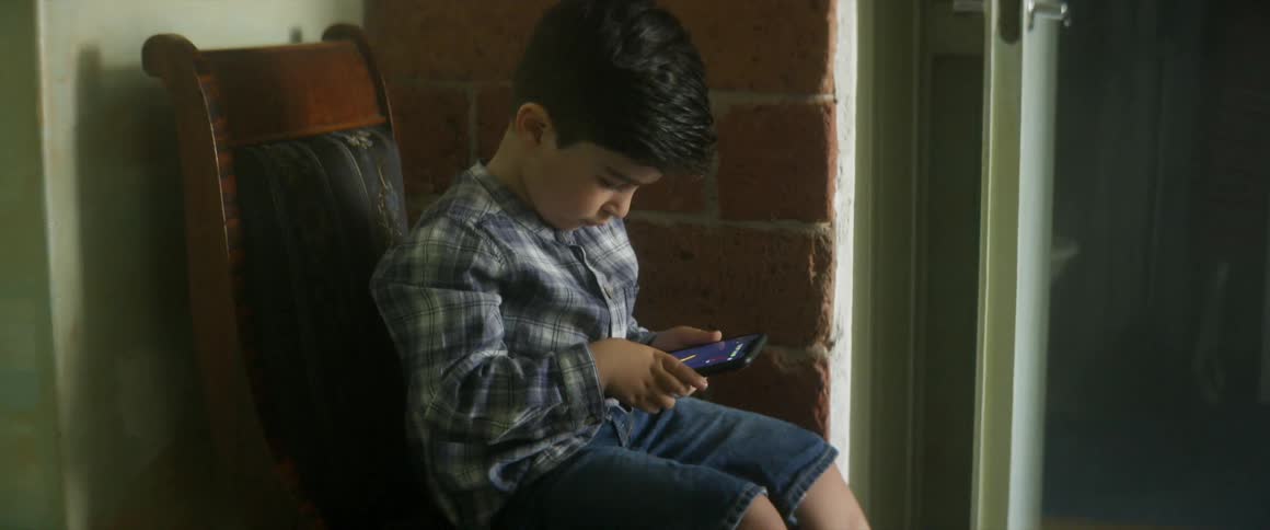 Child sitting in a chair plays on smartphone