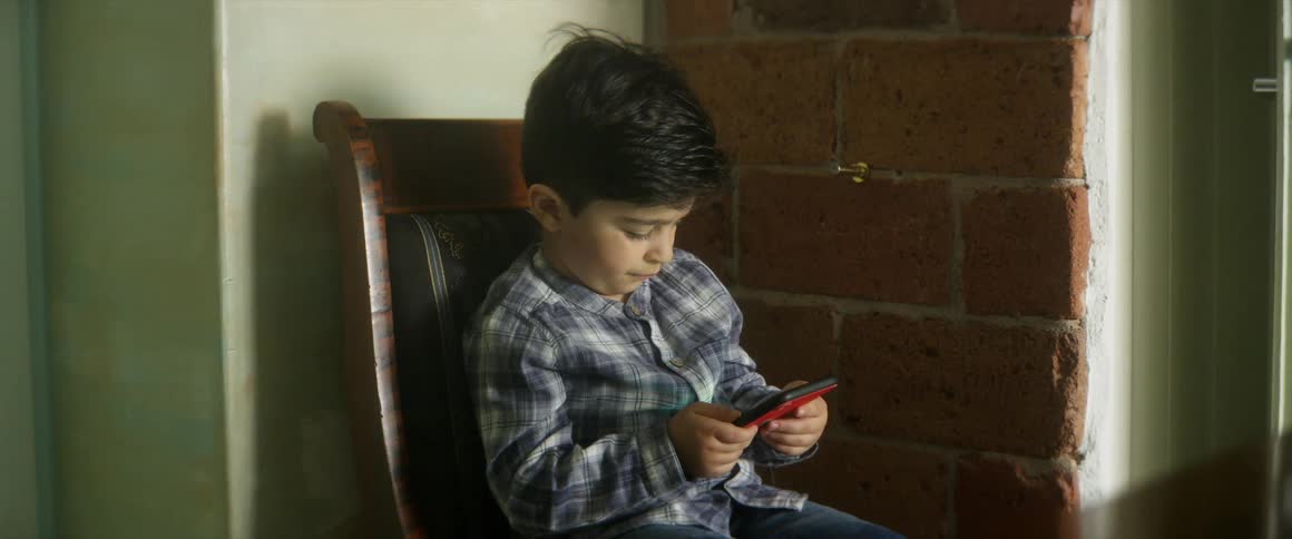 Young boy sitting down using a smartphone