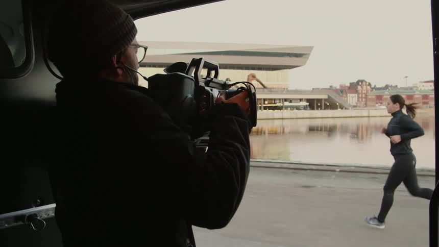 A photographer films a woman who is jogging