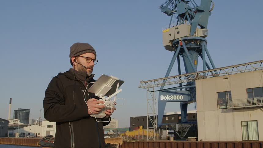 A man is standing outside looking at a computer screen