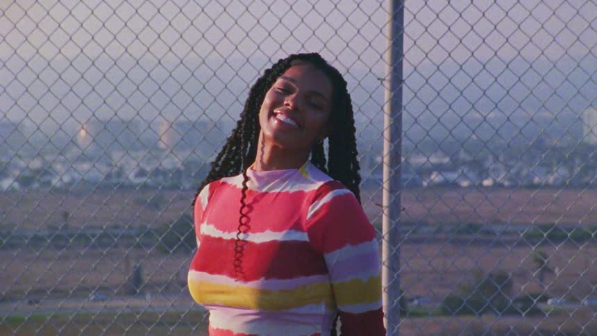 Pretty young black girl posing front of fence in the city