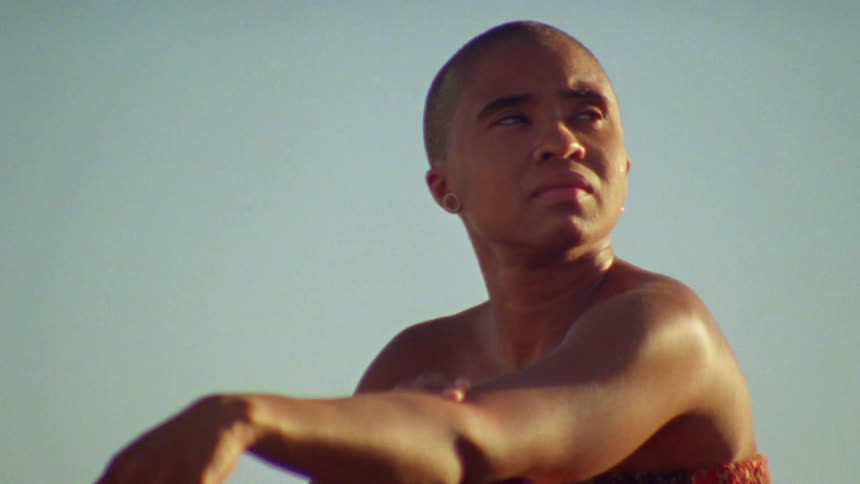 Bald woman wearing a dress sitting outdoors at sunset