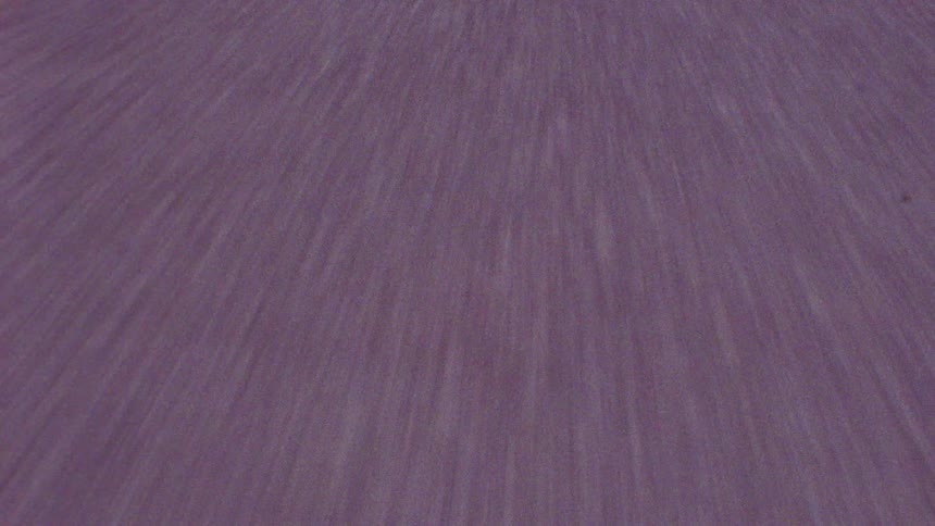 Camera shakily hovering over the asphalt on a road