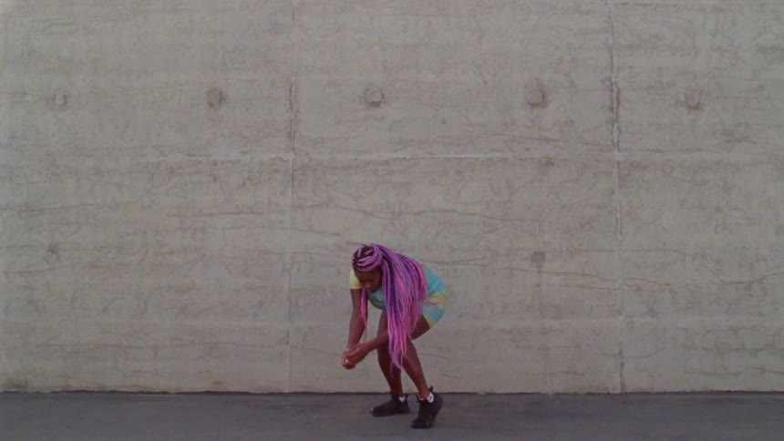 A woman is dancing by the concrete wall