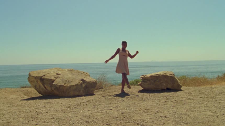A teenage girl dances on the shore