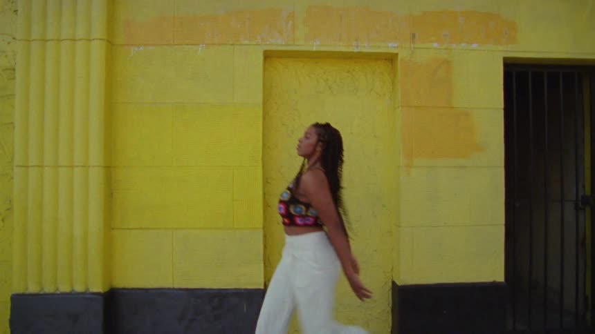 A woman is dancing in front of the yellow building