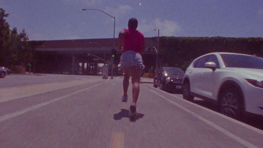 A bald woman running in the middle of the highway