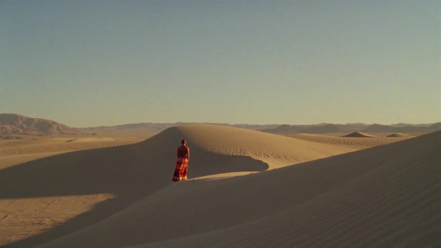 A woman walking down a sand dune