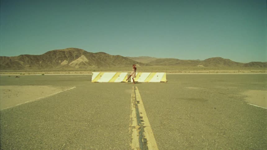 A person is dancing by the road barrier in the distance