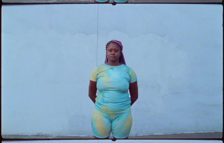 Woman looking at the camera standing in front of a blue wall