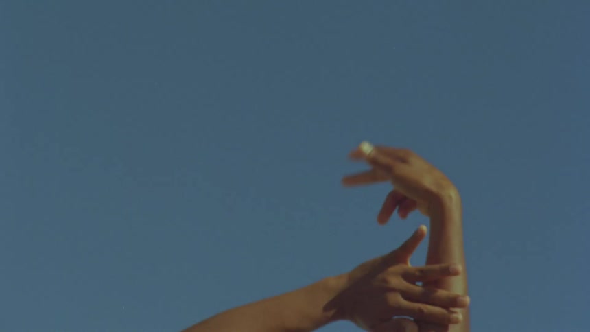 A person rubbing his arms and hands extended up against the blue sky