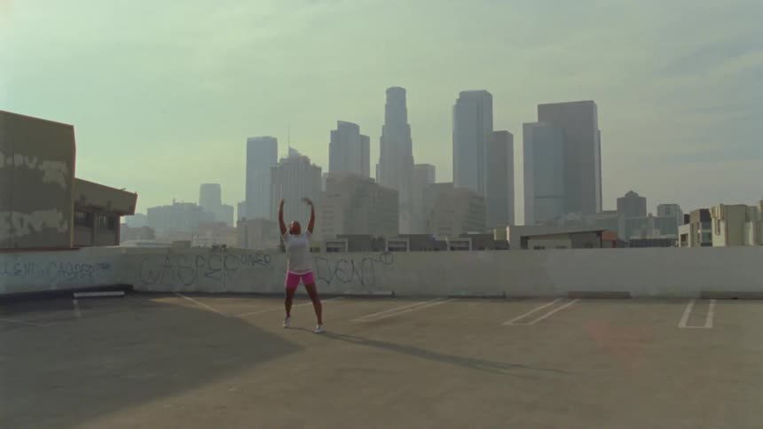 A woman is dancing in the parking lot on the roof