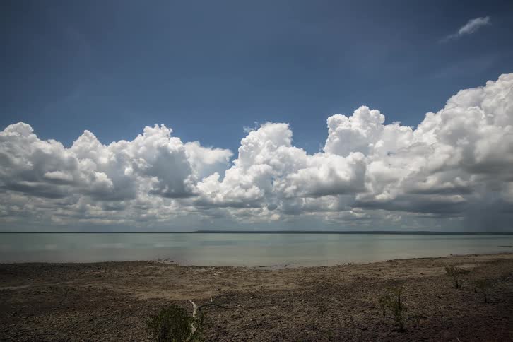 Cumulus clouds moving above lake along the shoreline
