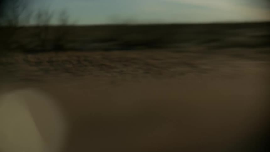 A truck drives down a road next to a field
