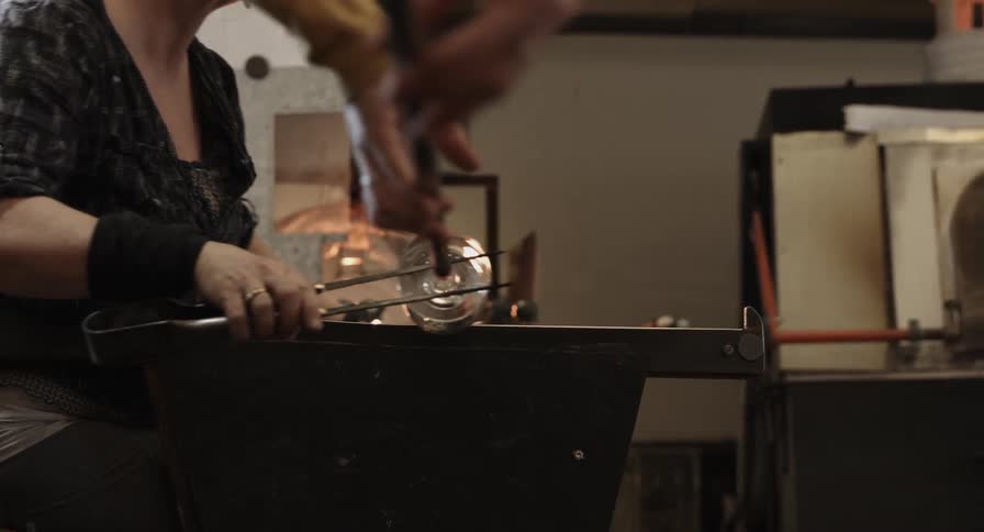 Two people roll out a piece of glass