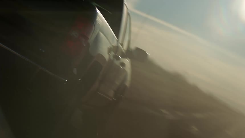 A pickup truck driving on a wet dirt road in the countryside
