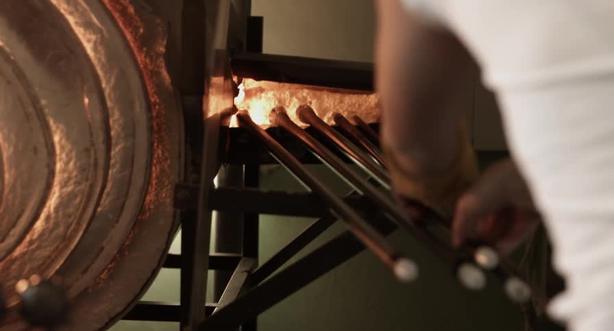 A person places rods into a heated structure/oven