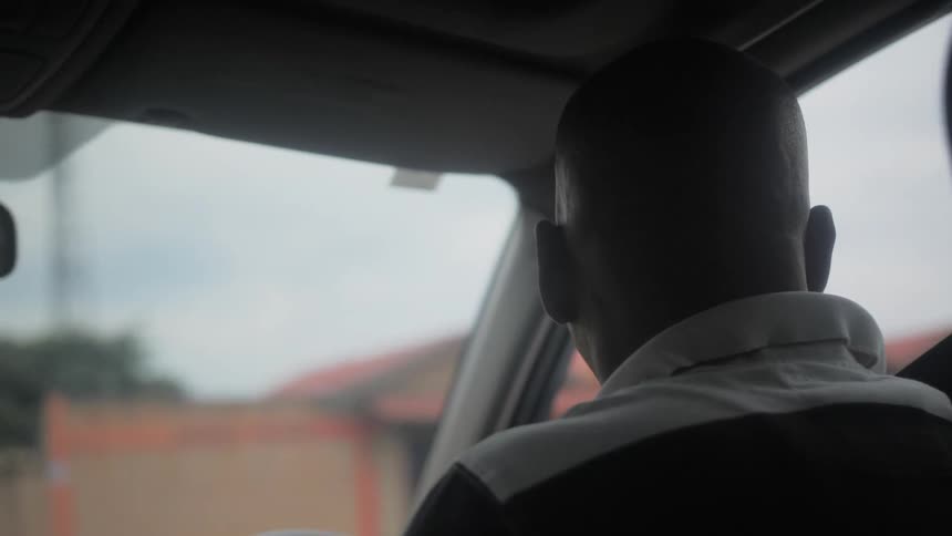 A man is driving a car through a city during the day
