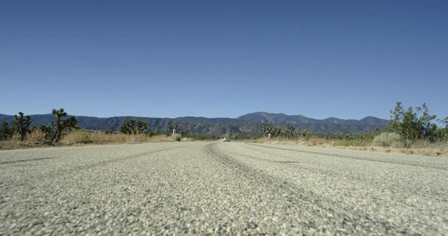 A car drives down a road next to a field
