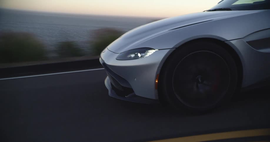 Sports car drives along highway overlooking ocean
