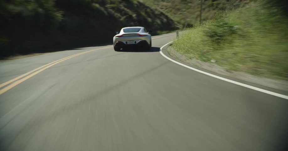 Sports car driving on a countryside road on the hills at daytime