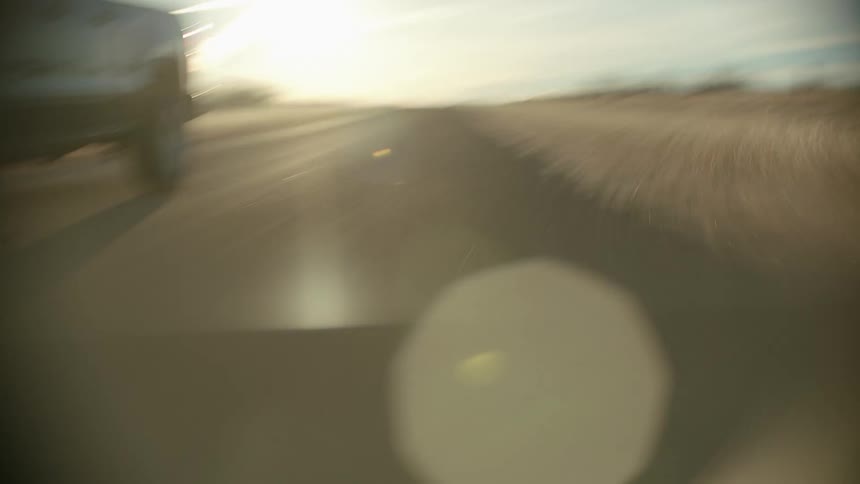 Out of focus pickup truck driving on a dirt rural road at sunset
