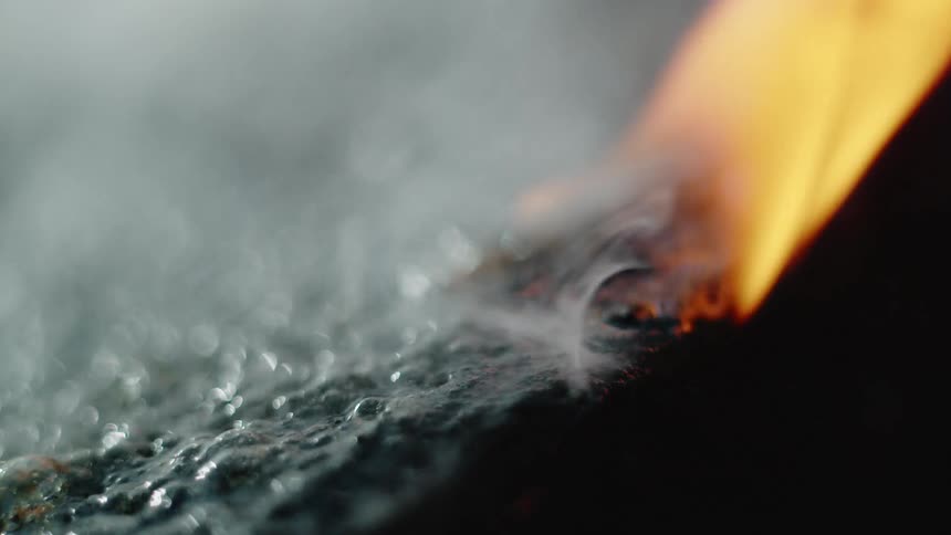 Fire and smoke over a bubbling boiling black surface