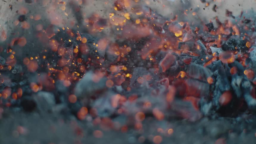 Mound of smoldering coals exploding in a shower of embers