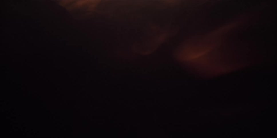 Camera traveling down burning log through flame and darkness.
