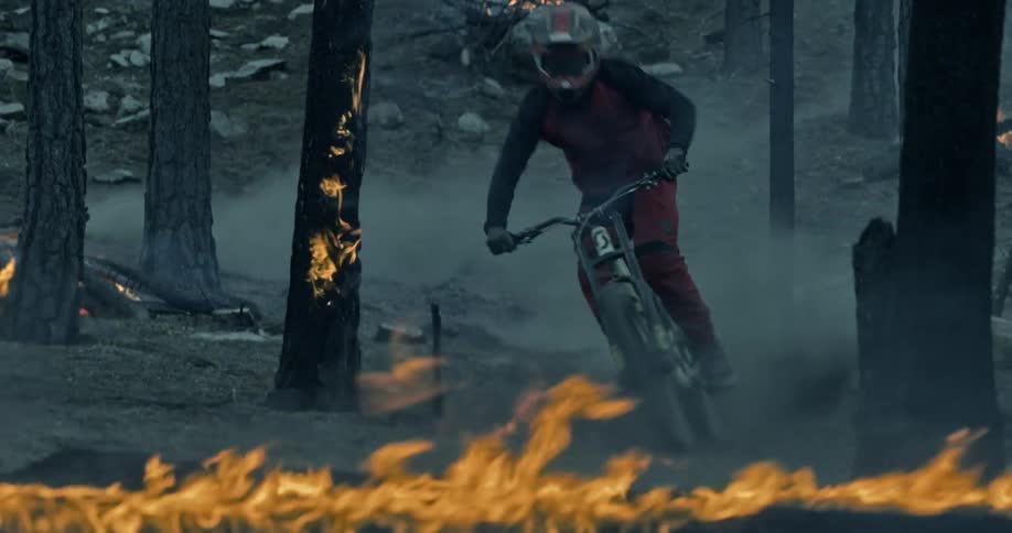 A man riding a mountain bike on a trail through a burning forest
