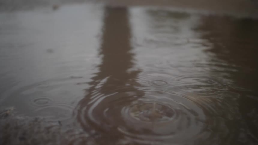 Rain is falling in a puddle outdoors
