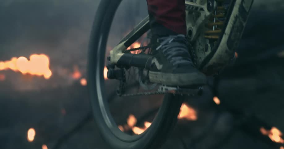 Cable cam mountain biker through burning forest.