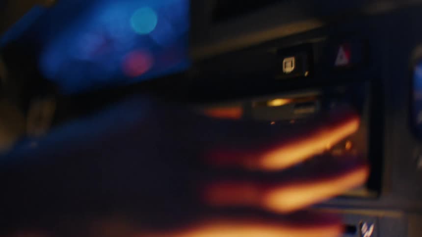 A person ejecting a cassette from a radio on the dashboard of a car