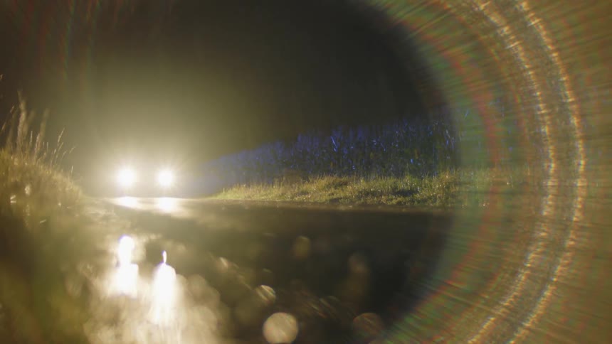A car is driving at night during the rain