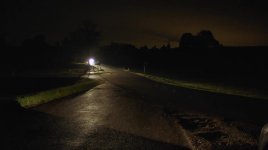 A car is driving on a road at night