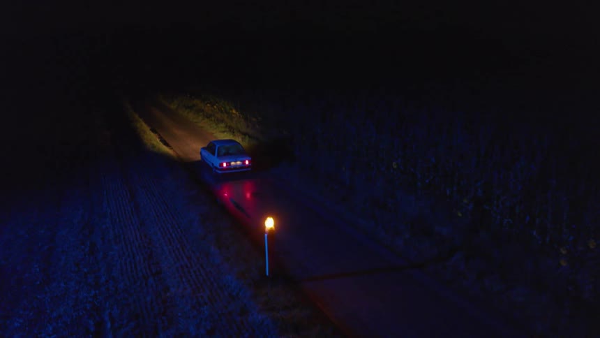 A car is driving down a road at night