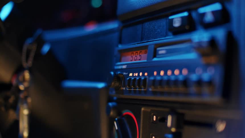 A person presses the button on their car radio