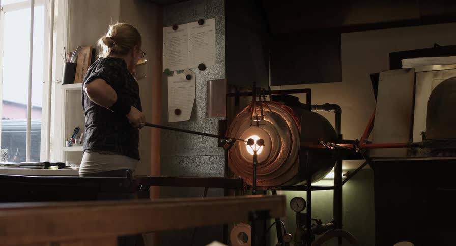 A woman is heating glass in an oven