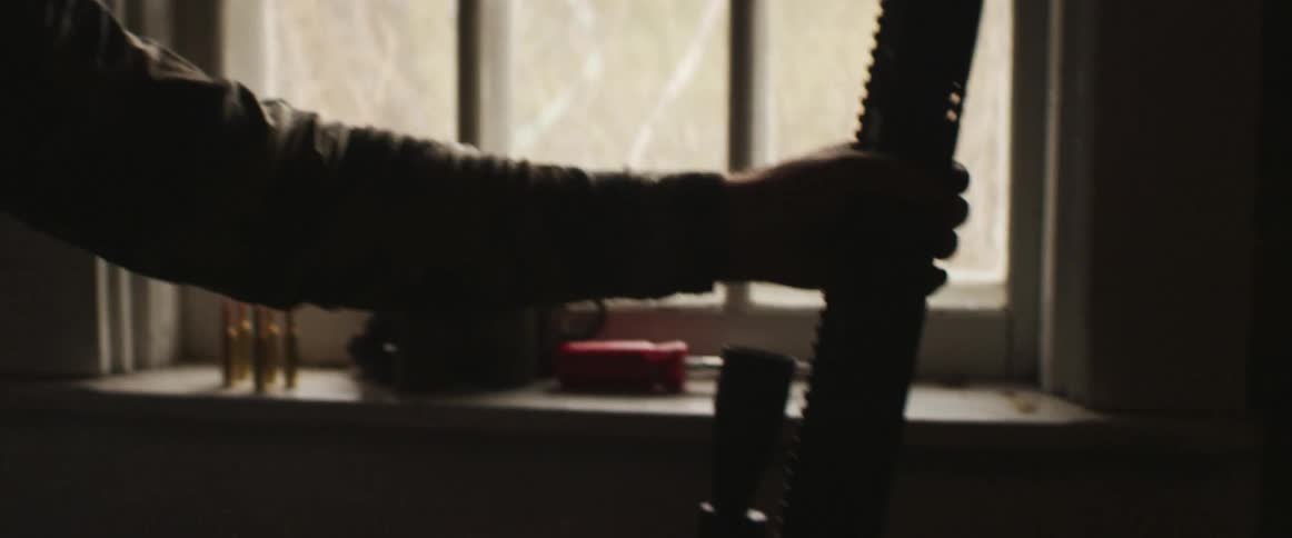A man indoors sets his gun down