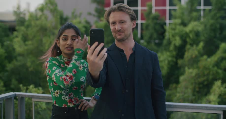 A man and woman stand together and take a selfie with a cell phone